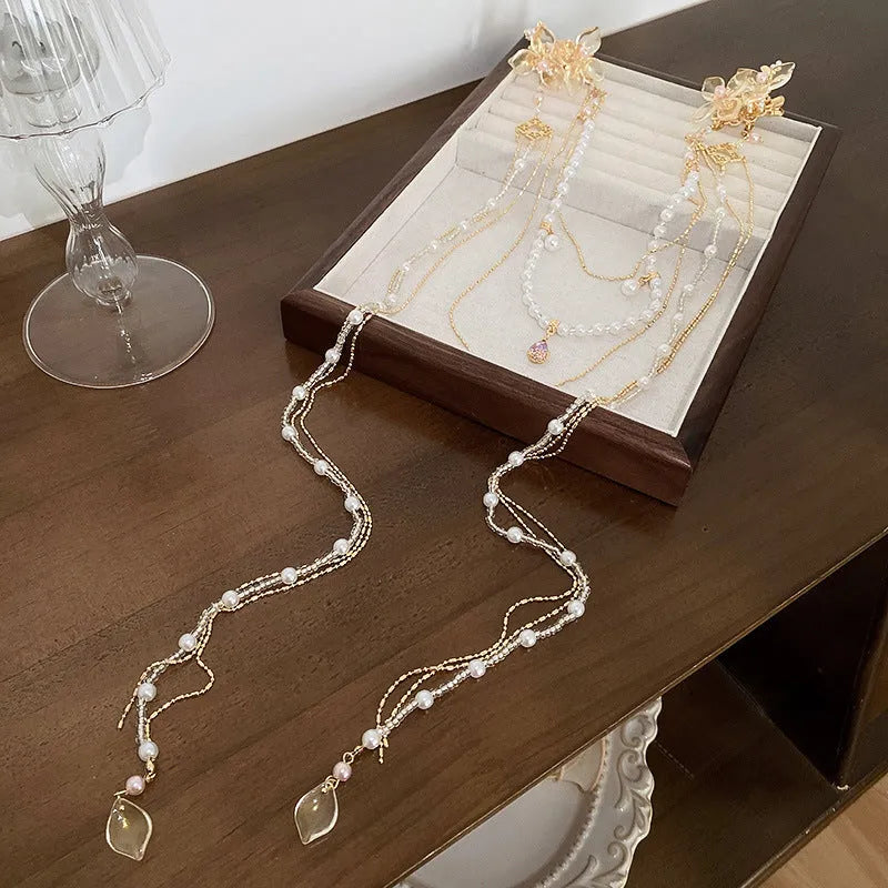 Gold women's hairpin with pearl, diamond acrylic details and a long tassel.