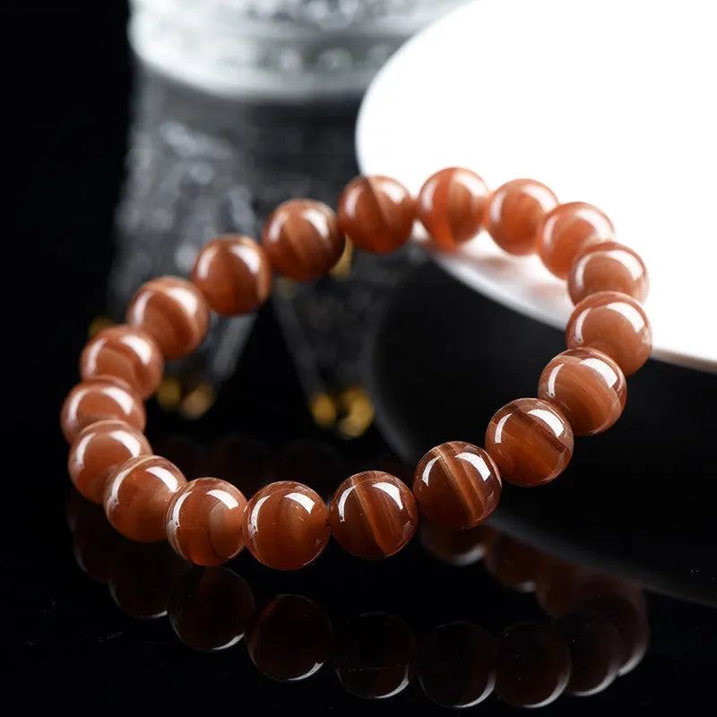 Natural rhodochrosite round bead bracelet with ruyi design on wrist.