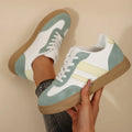 Green women's retro trainers with a cross strap design, round toe, and white rubber sole.