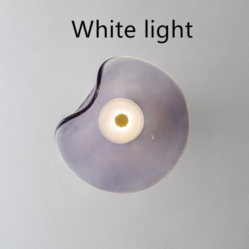 Round glass wall lamp in a choice of colours for bedroom bedside lighting.