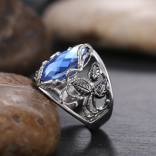 Close-up of a blue crystal horse eye-shaped geometric alloy ring on a person's finger.