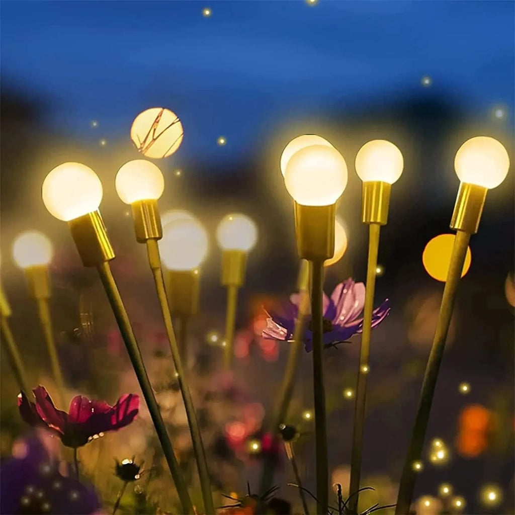 Solar-powered LED firefly lawn light with ground stake inserted in grass