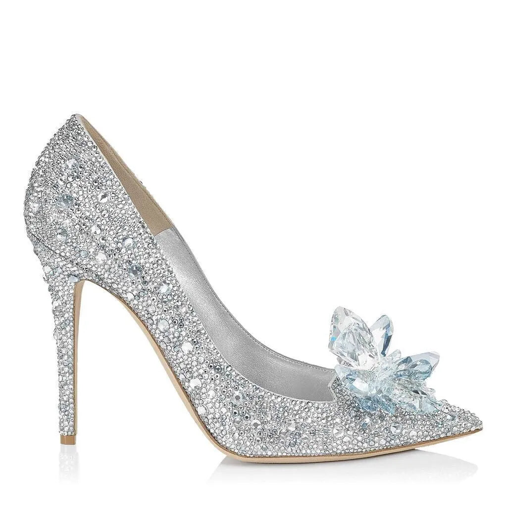 Gold women's high heels with pointed toe, rhinestone details, bow and stiletto heel on a plain background.