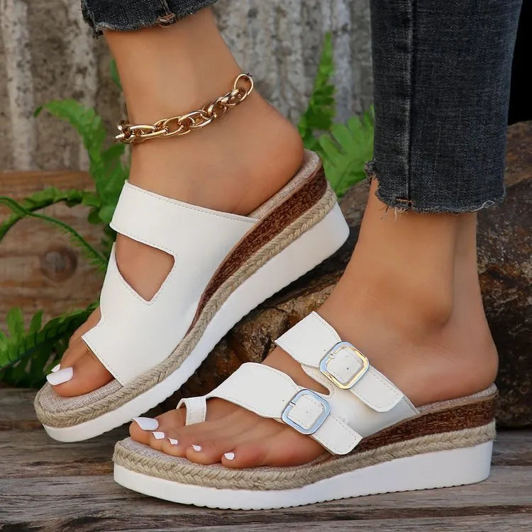 White patent leather wedge sandals with woven upper and peep toe design on a neutral background