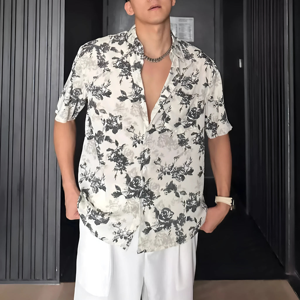 Man's loose fit black short sleeve shirt with floral pattern, worn open in cardigan style.