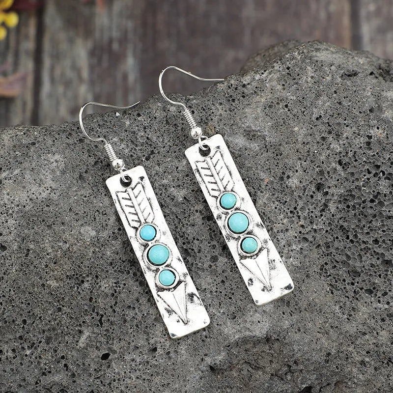 Silver long drop earrings with turquoise inlay and a geometric shape.