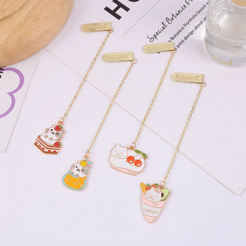 Metal cartoon cat bookmark with food-themed designs including strawberry cake and fruit roll styles