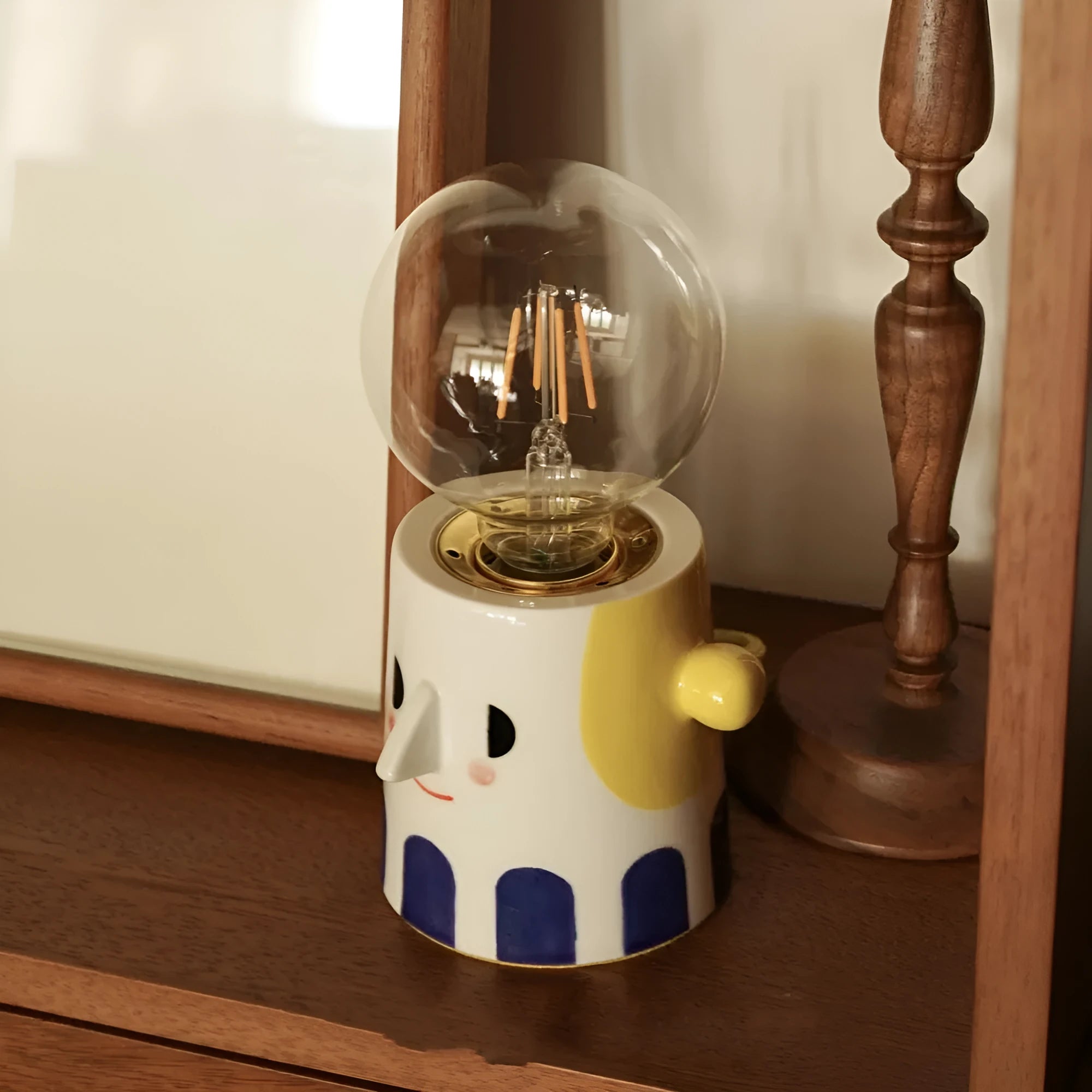 Handmade ceramic table lamp with ball headlight design on wooden surface