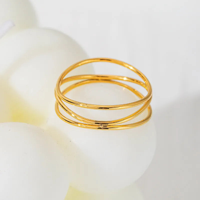 Gold titanium steel ring with a three-layer geometric coil line design on a finger.