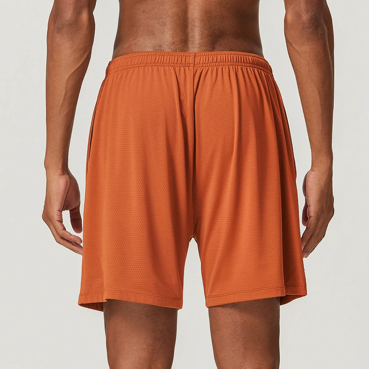Men's double-layer quick-drying running shorts in brick red colour on a mid-waist model.