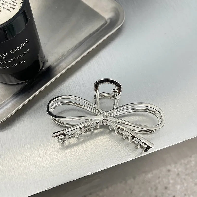 A silver and a gold alloy hair barrette with a prominent bow design.
