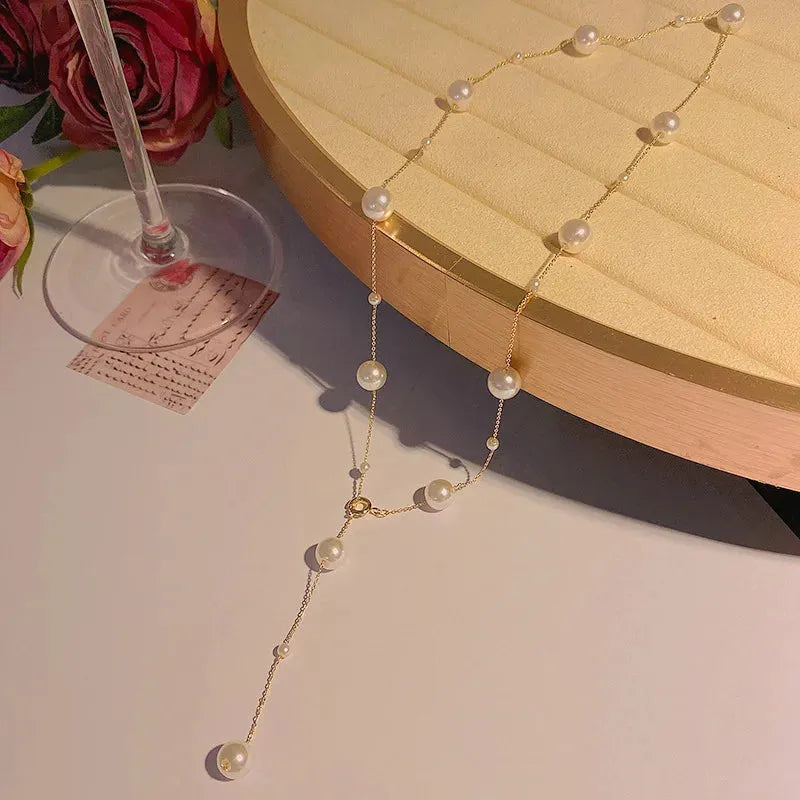 Gold starry pearl choker necklace on a white surface showing imitation pearl chain