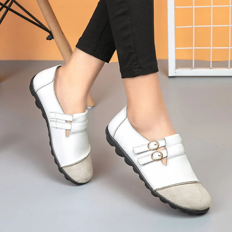 A pair of casual black flat shoes with a round toe, Velcro strap, and cow split leather upper.