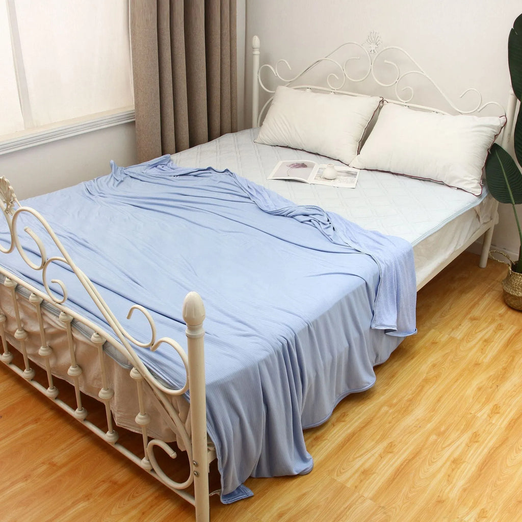 Blue and grey cooling blanket with Japanese Q-Max fibres on a bed.