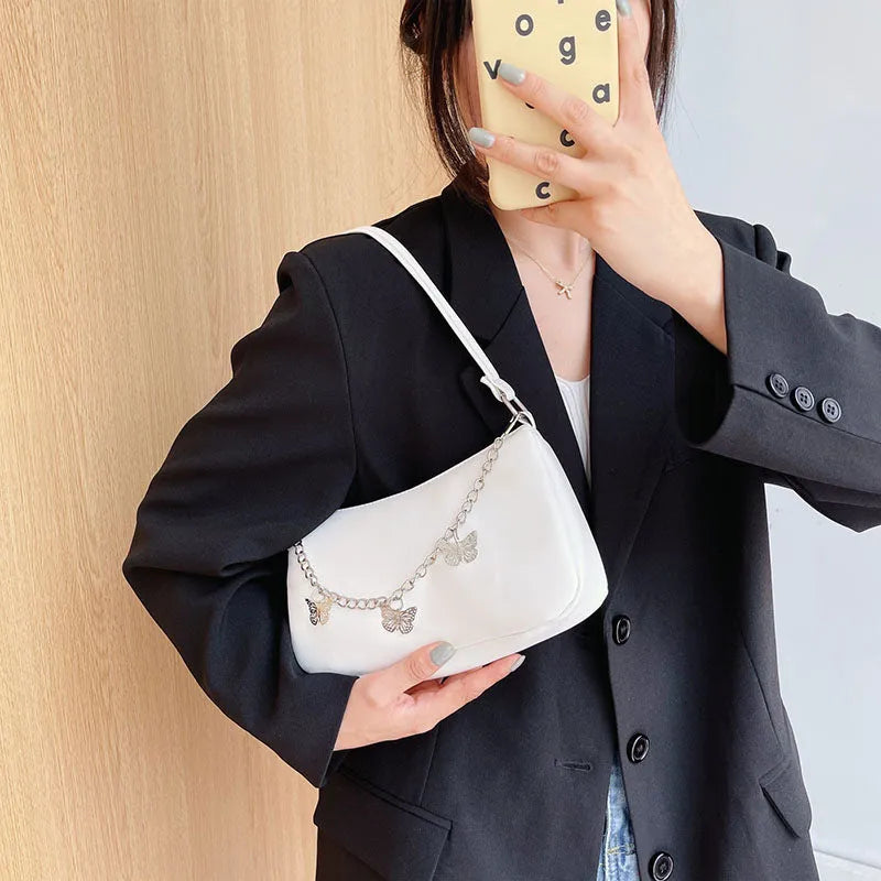 Square black PU leather crossbody bag with a butterfly chain strap and external structured pocket.