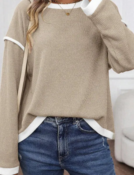 A beige loose knit top with a four leaf clover print and contrasting trim on the sleeves and hem.