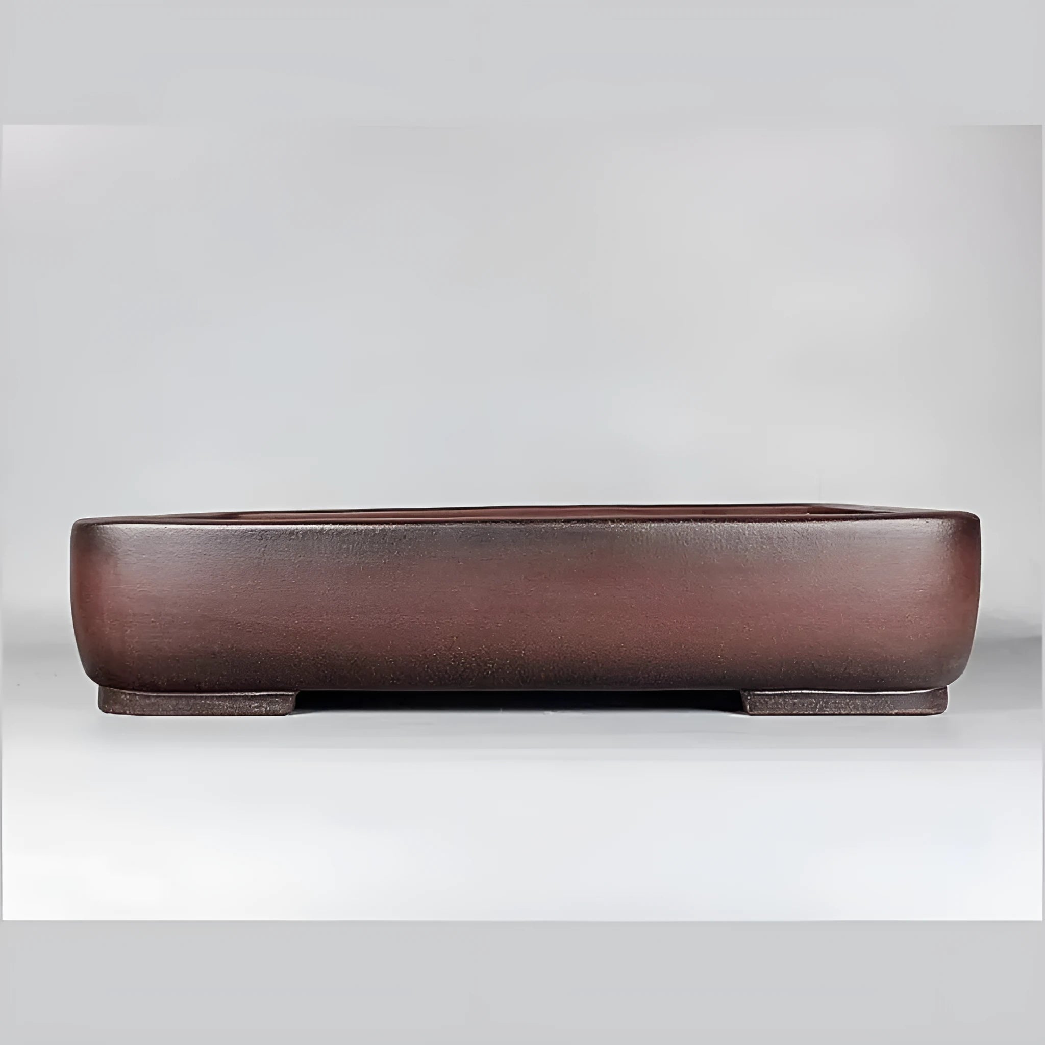 Handmade rectangular purple clay flower pot for indoor plants on a table.
