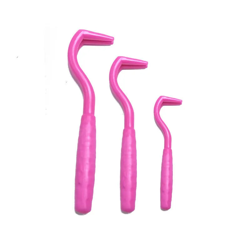 Three plastic tick removal hooks for dogs, shown in assorted colours on a white background.