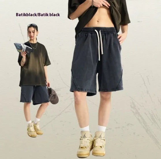 Man wearing loose fit batik washed cotton terry shorts with patch craft detailing in a street fashion style.