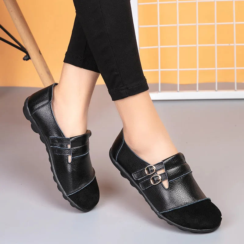 A pair of casual black flat shoes with a round toe, Velcro strap, and cow split leather upper.