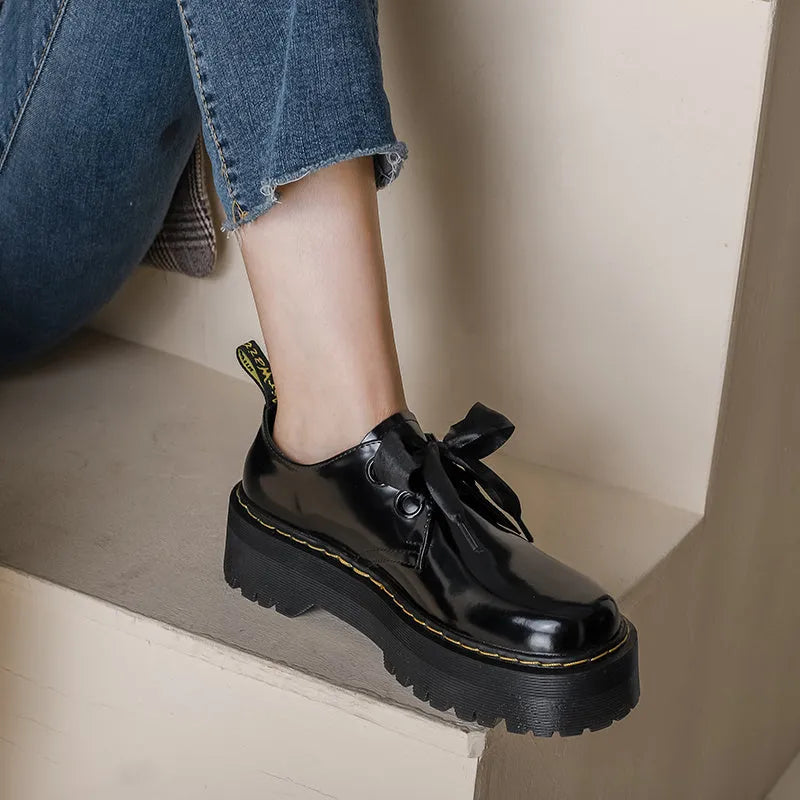 Women's black leather shoes with thick soles, cross straps, and ribbon lacing shown from side view