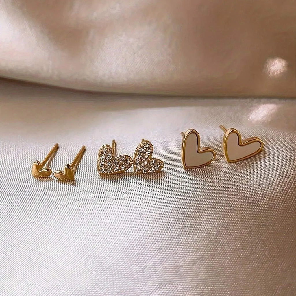 Set of three pairs of women's heart-shaped alloy drop earrings in gold, black, pink colours.