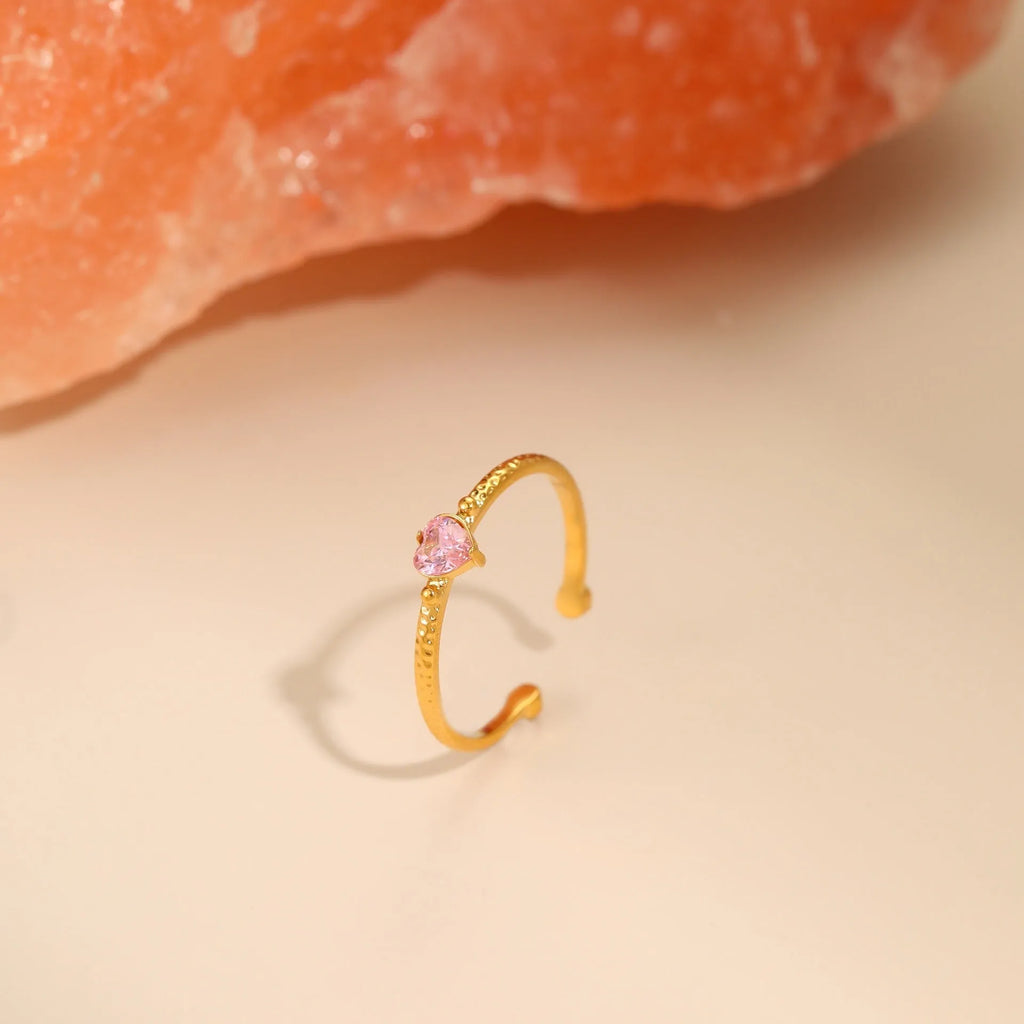 Open ended stainless steel ring with a geometric zircon-inlaid heart in white, pink, or green.