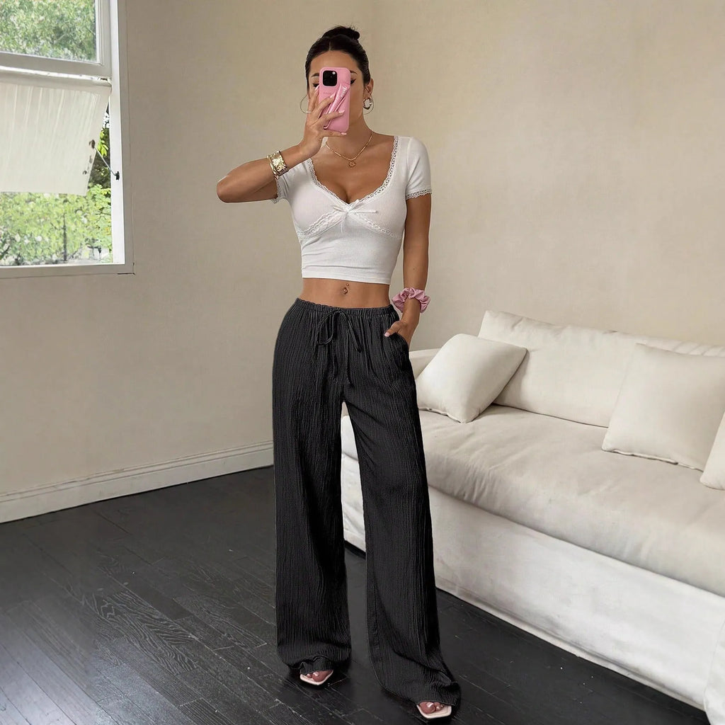 Women's black wide-leg trousers with a white lace-up detail at the mid waist on a hanger.