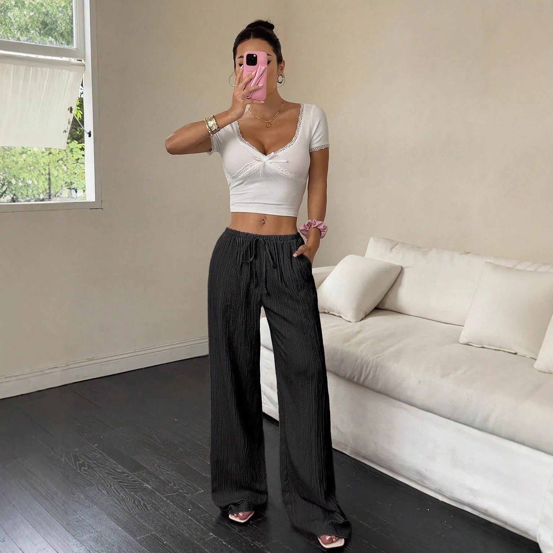 Women's black wide-leg trousers with a white lace-up detail at the mid waist on a hanger.