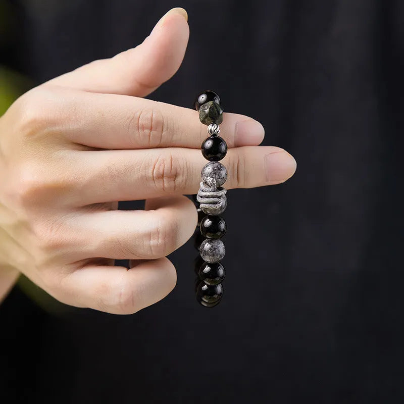 Men's S925 sterling silver bracelet with a black obsidian snake charm on a dark background.