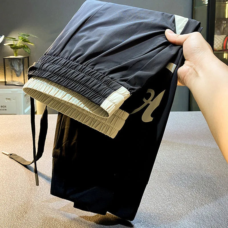 Men's solid black cotton trousers with elasticated ankle bands, shown in a casual style.