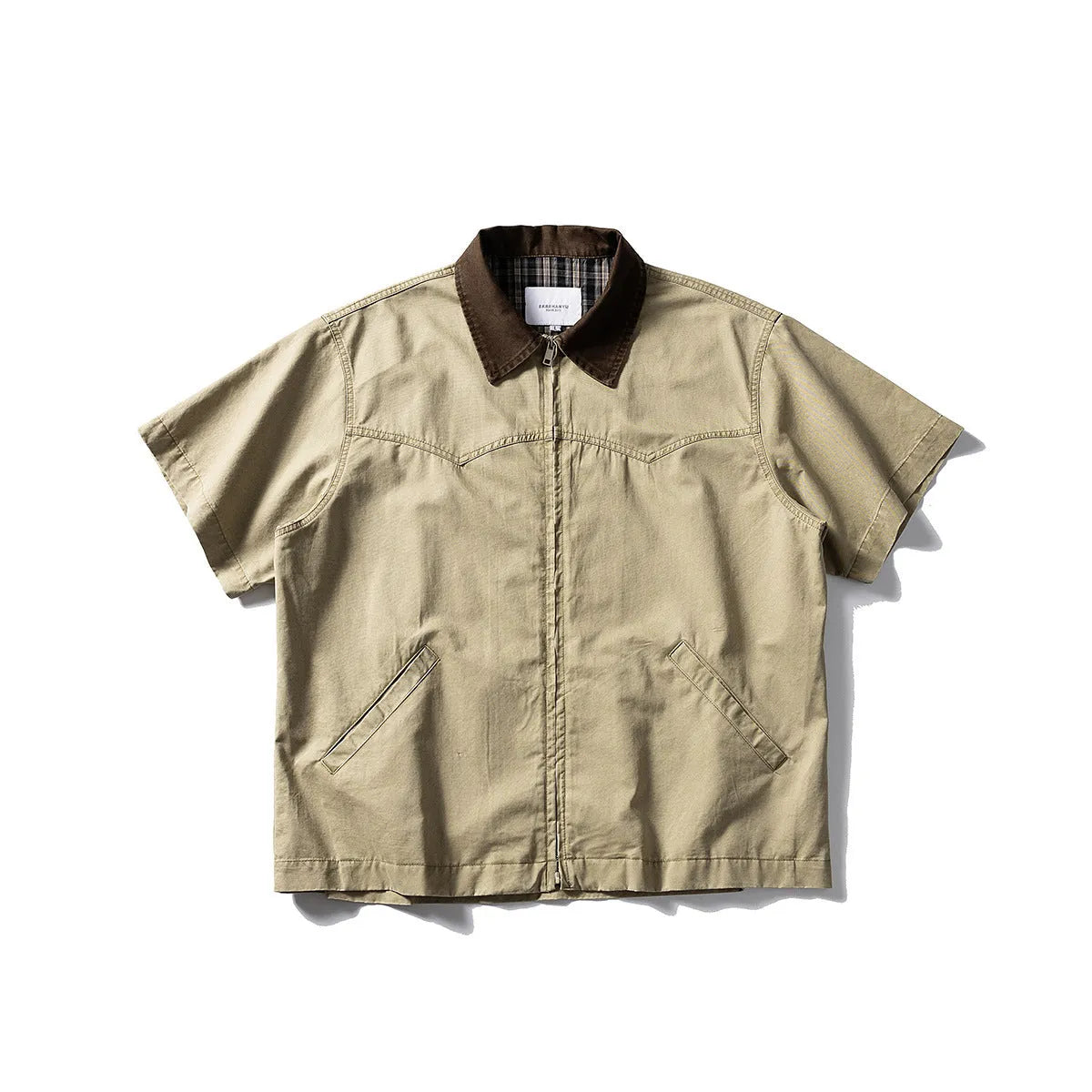 Washed khaki loose-fit cotton overalls shirt with short sleeves on a hanger.