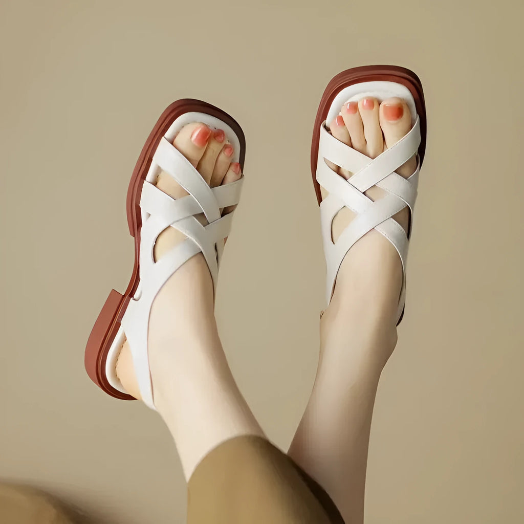 Women's glossy patent leather sandals with a square toe and flat low heel in black.