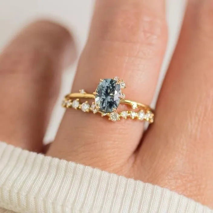 Gold-plated women's ring with green zircon stones and floral engraving on a white background.