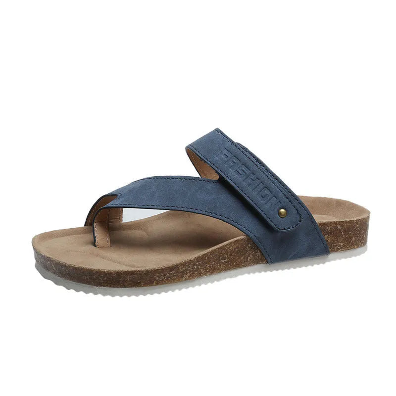 Thick-soled blue flip-flops with flat toe ring design on beach background