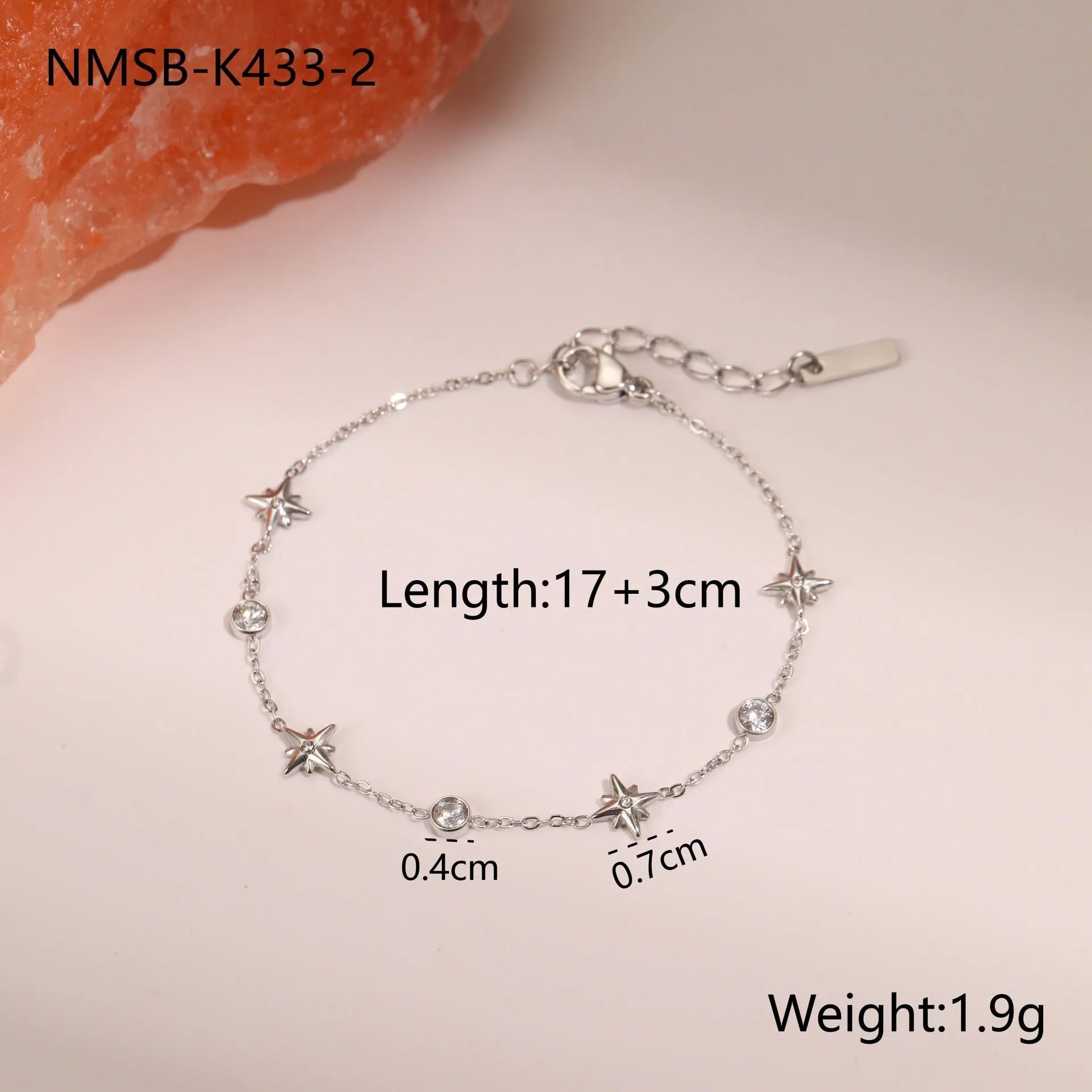 Gold plated stainless steel bracelet with a detailed zircon star pendant on a woman's wrist.