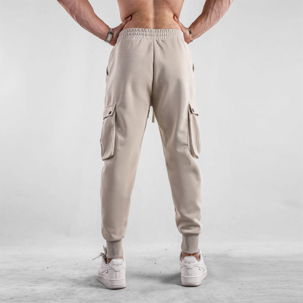 Men's loose fit cotton trousers with ankle-tied cuffs and multiple pockets in a light grey colour.