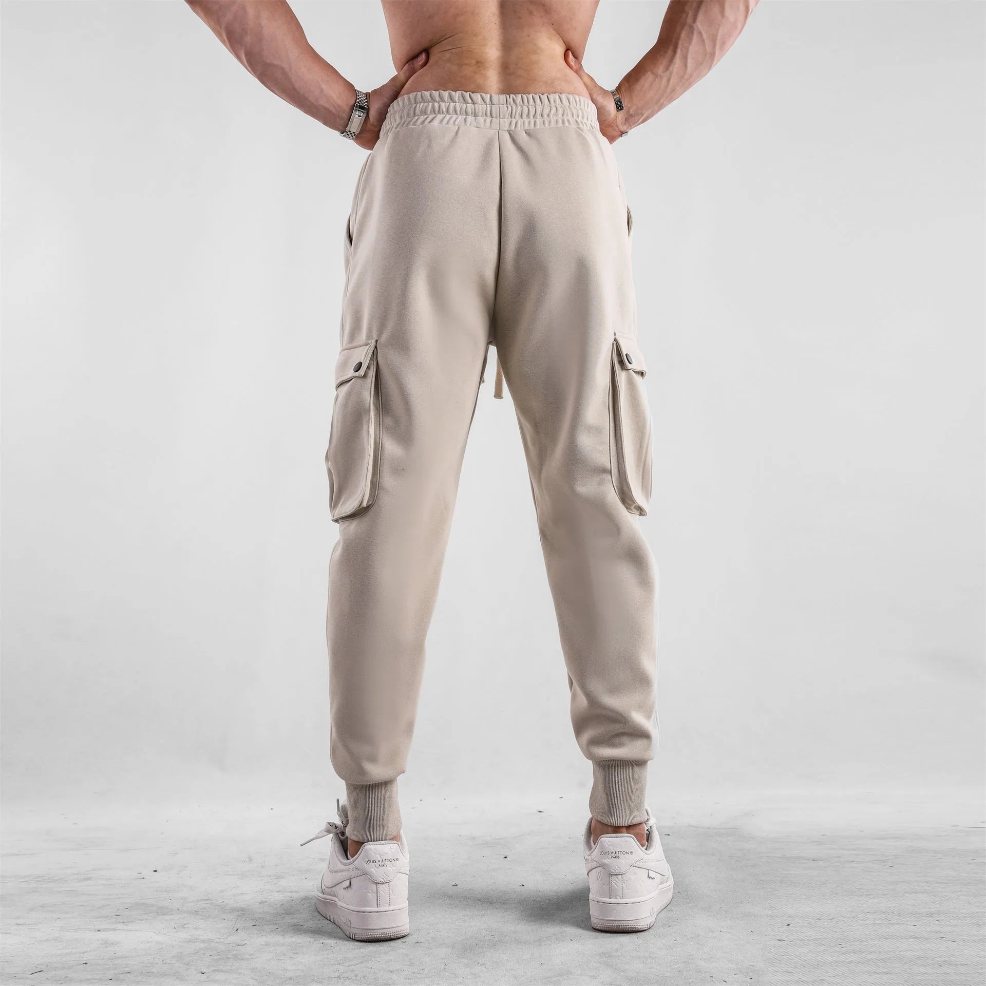Men's loose fit cotton trousers with ankle-tied cuffs and multiple pockets in a light grey colour.