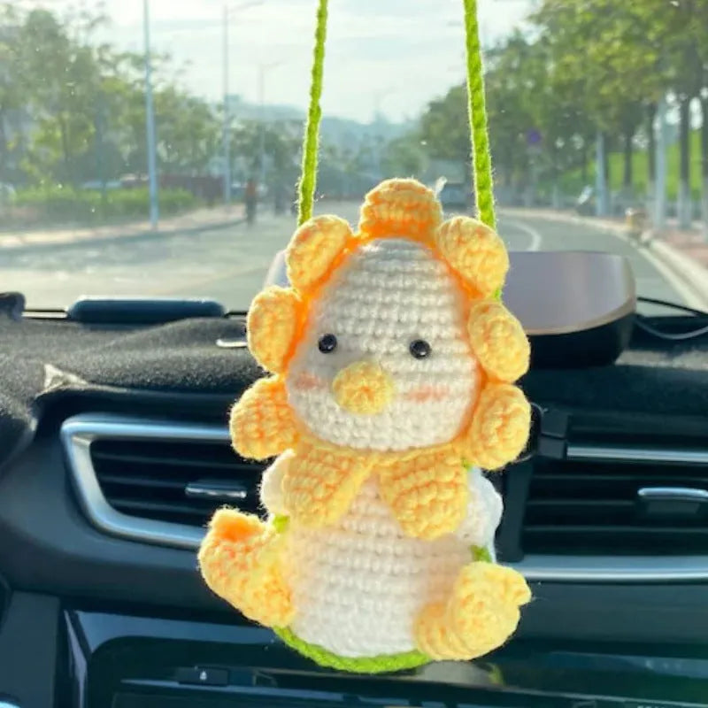 Green and white crochet wool car plant decoration with hanging rope on car dashboard