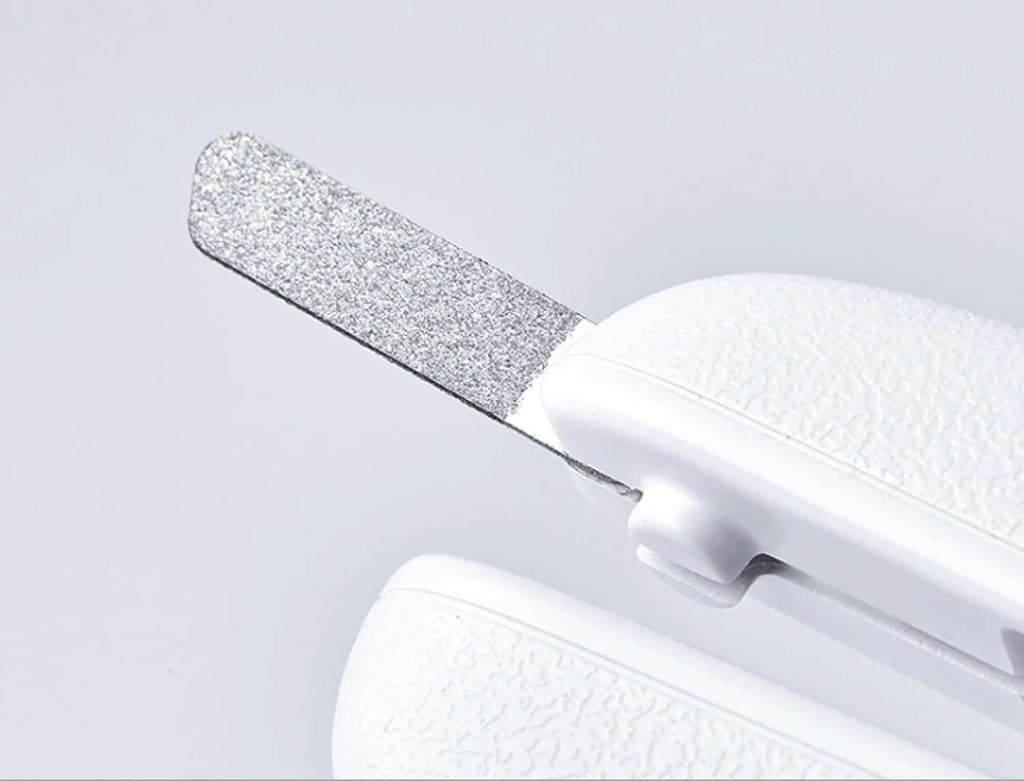 White pet nail clippers with LED light, anti-splash guard, and a nail file on a table.