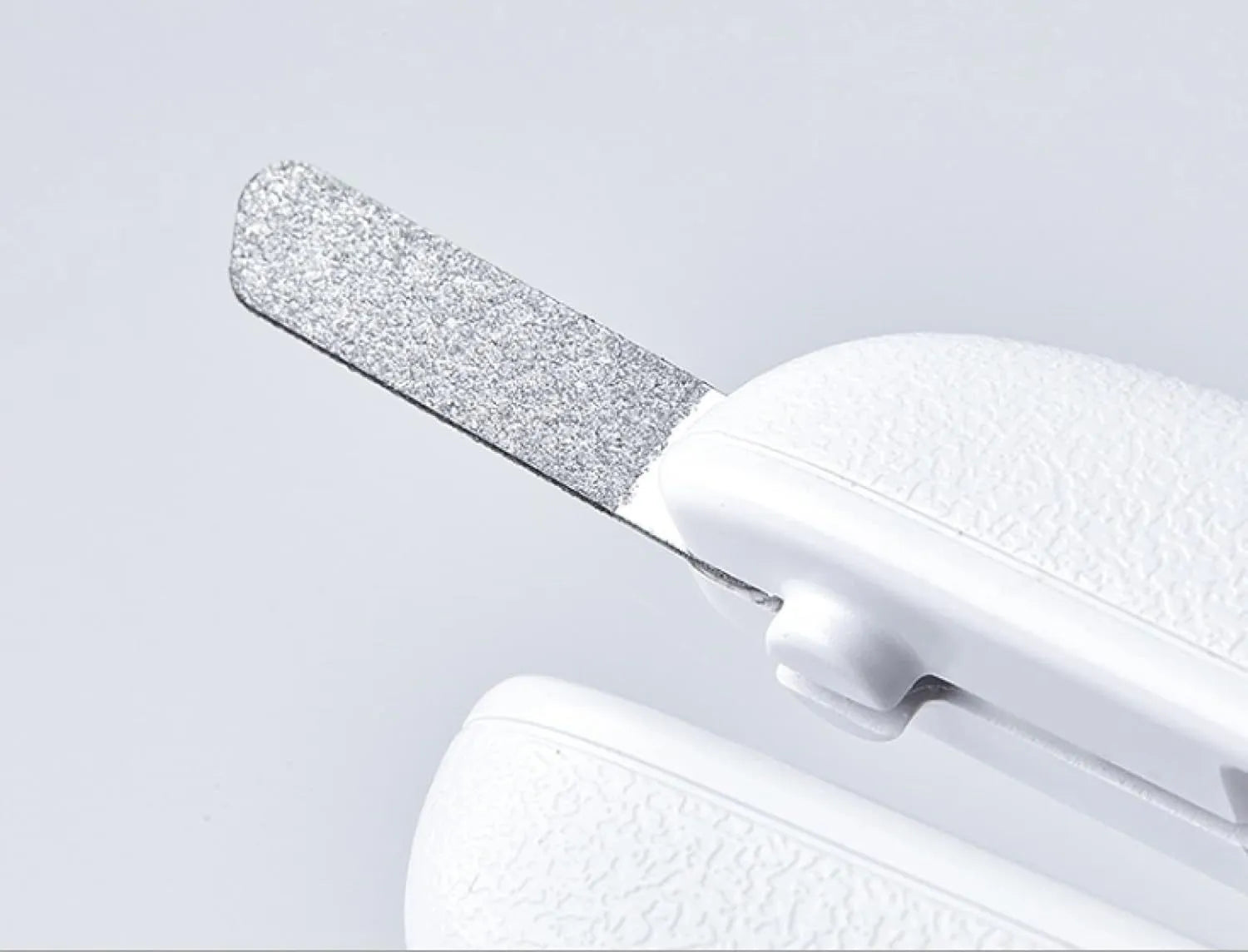White pet nail clippers with LED light, anti-splash guard, and a nail file on a table.