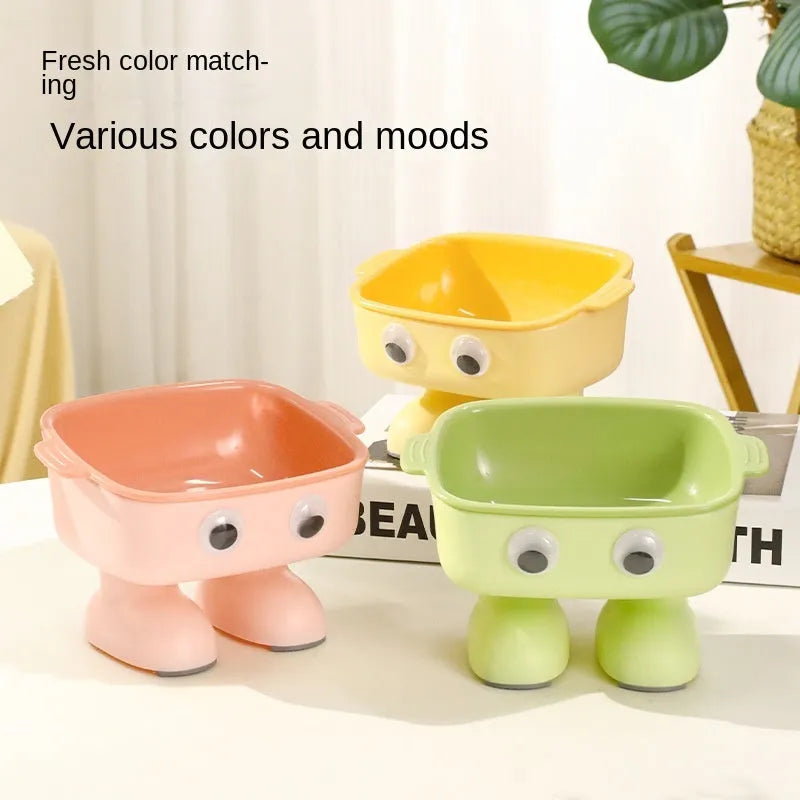 Green robot-shaped elevated cat bowl with tilted food dish and non-slip base.