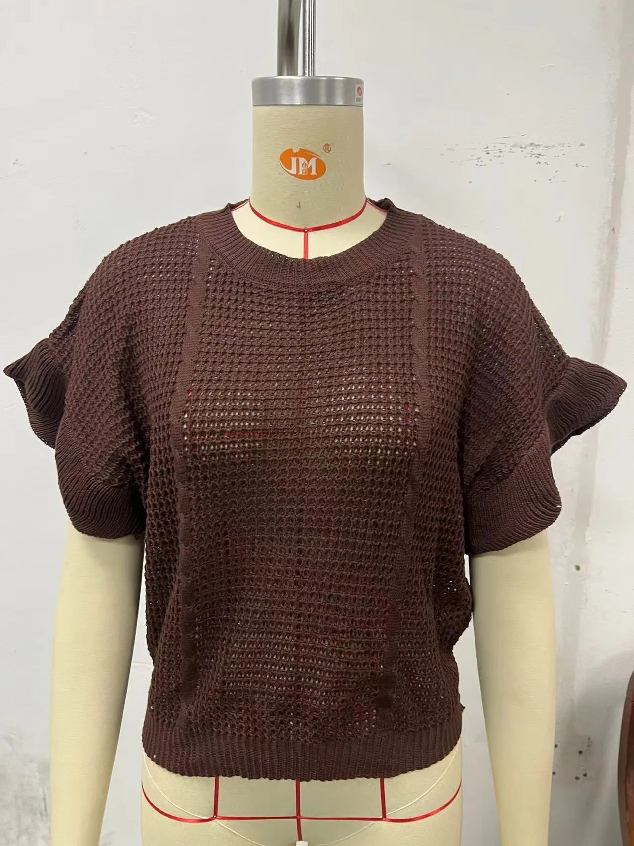 White loose knitted women's pullover sweater with ruffled short sleeves and a textured 3D pattern.