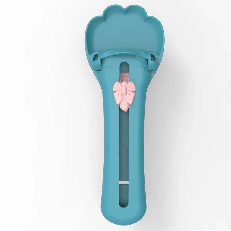 Green and pink pet food scooper spoon with squeezer handle and extruded feeder tip for dispensing treats.