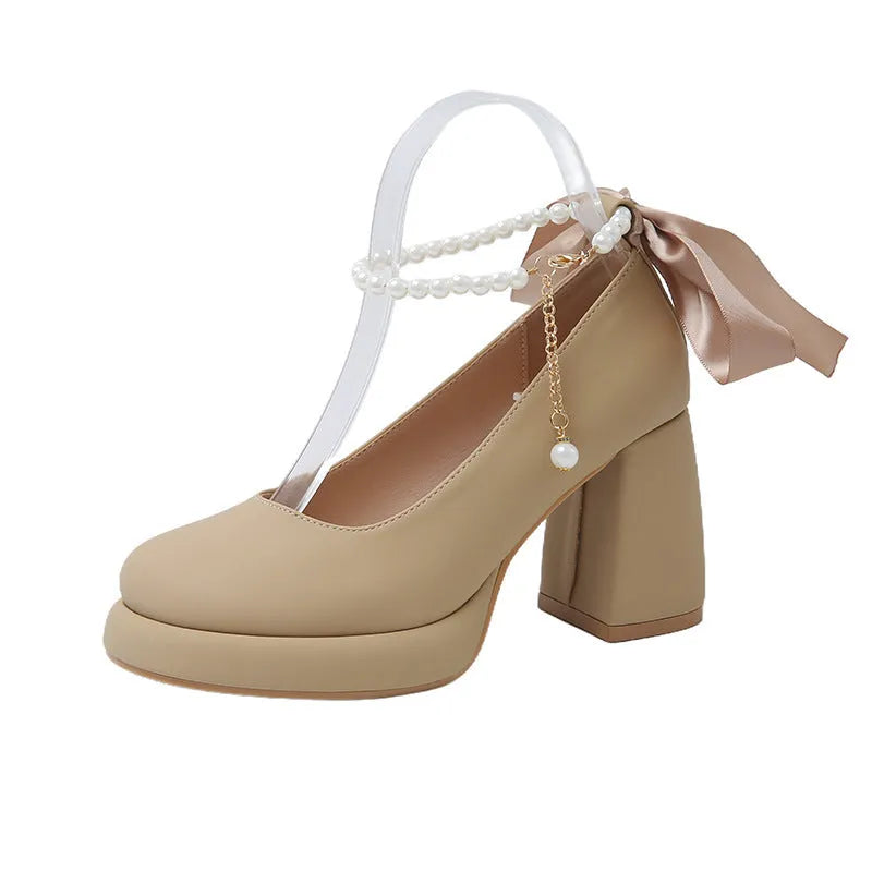 Beige women's Mary Jane shoes with a chunky heel, round toe, and ankle strap with a pearl and buckle.