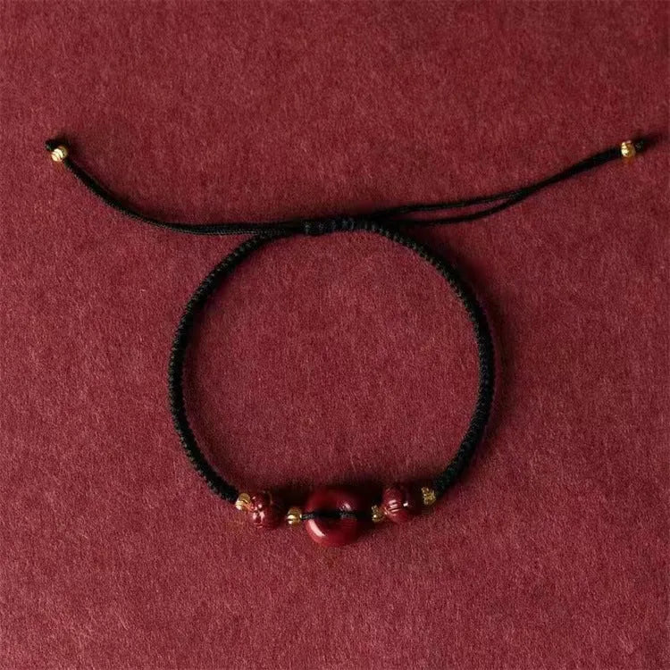 Heart-shaped cinnabar bead on an adjustable knot rope bracelet with a decorative peace buckle closure.