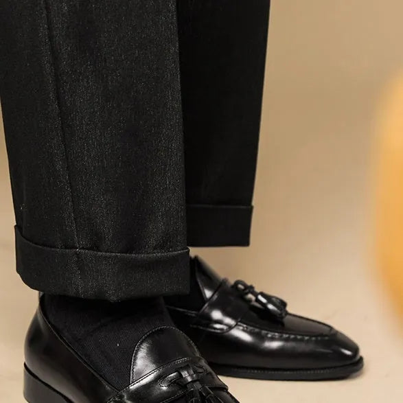 Men's black polished leather tassel loafers on a white background