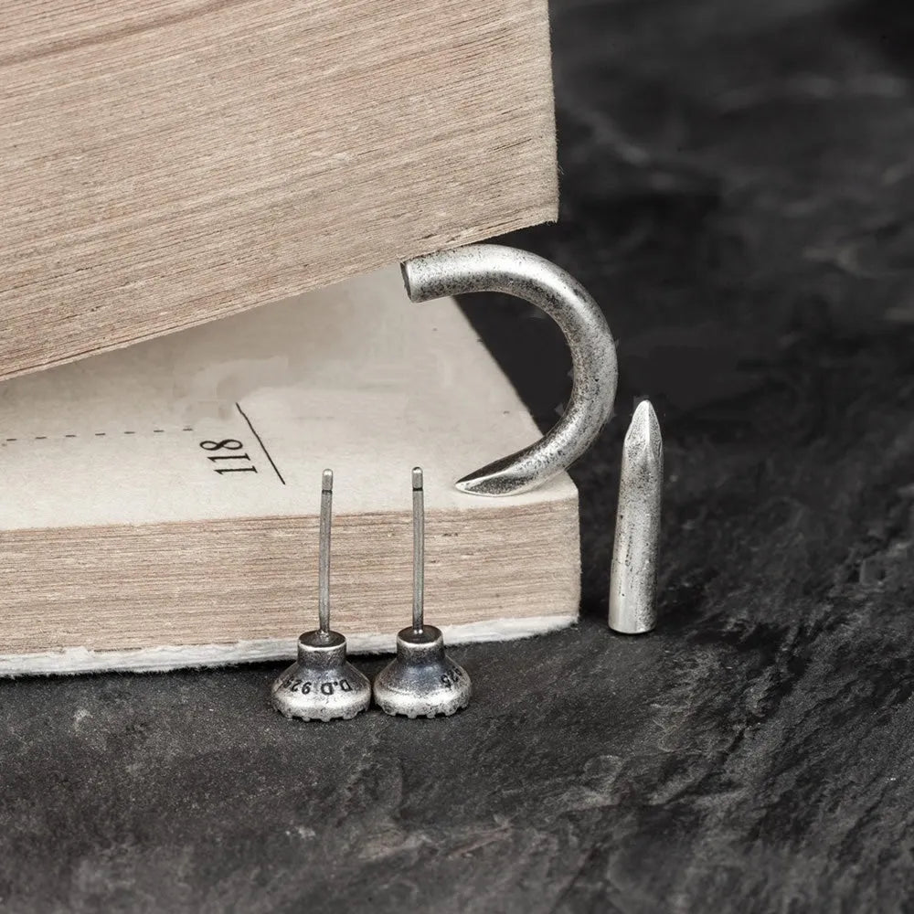 Close-up of a sterling silver S925 punk-style earring shaped like a retro nail, shown on a hook back.