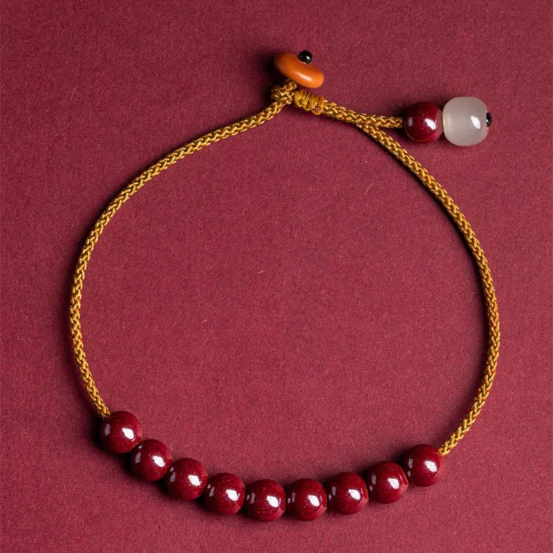Close-up of a hand-woven geometric bracelet made from cinnabar and Hetian jade stones.