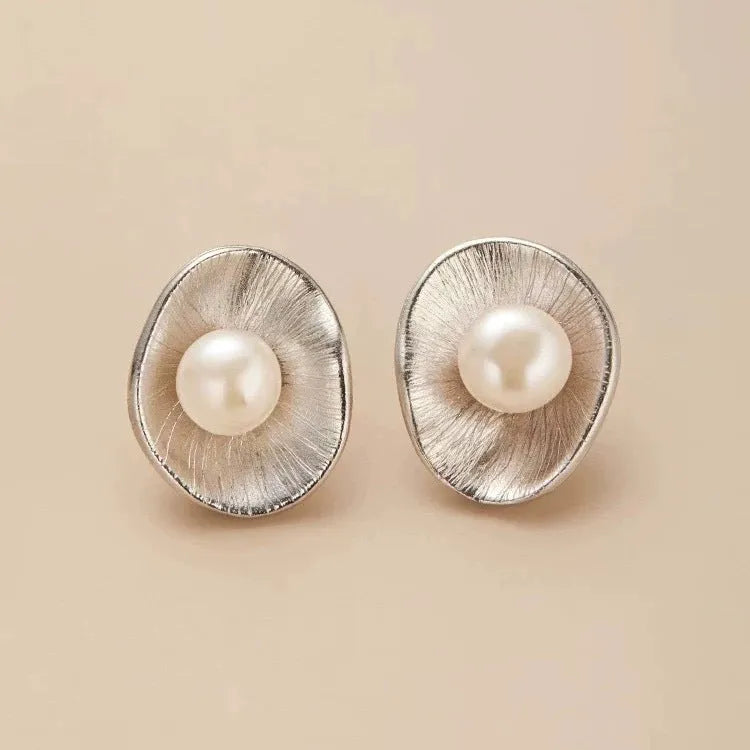 A pair of gold geometric sterling silver ear studs with small white pearl details on a post back.